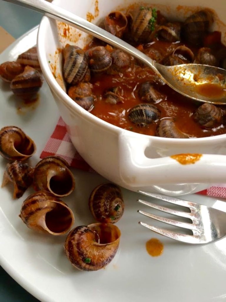 A dish of escargots in garlic butter on a checked tablecloth